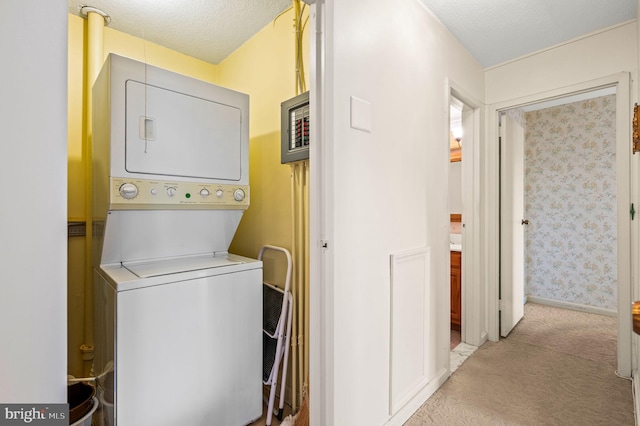 clothes washing area with stacked washing maching and dryer and a textured ceiling