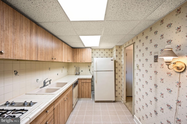 kitchen with decorative backsplash, white appliances, light tile patterned flooring, a drop ceiling, and sink