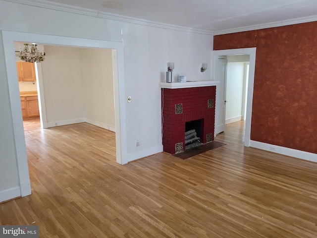 unfurnished living room featuring wood-type flooring, a brick fireplace, crown molding, and a chandelier