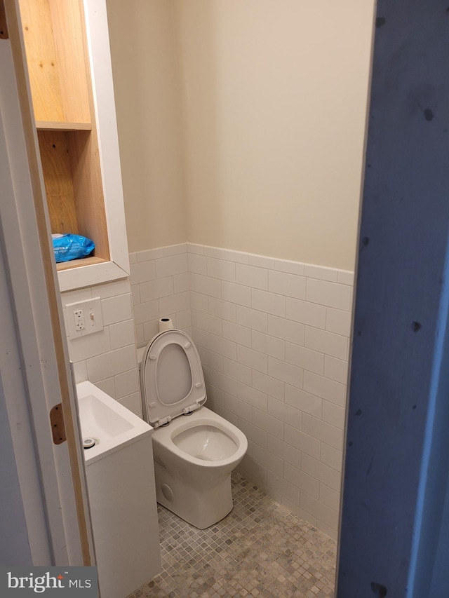 bathroom featuring toilet, vanity, tile walls, and tile patterned floors