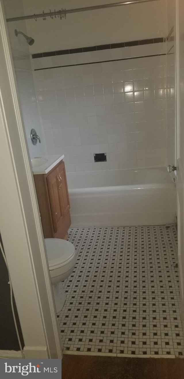 full bathroom with toilet, tile patterned flooring, tiled shower / bath combo, and vanity