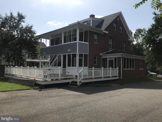 back of property with a wooden deck and a sunroom