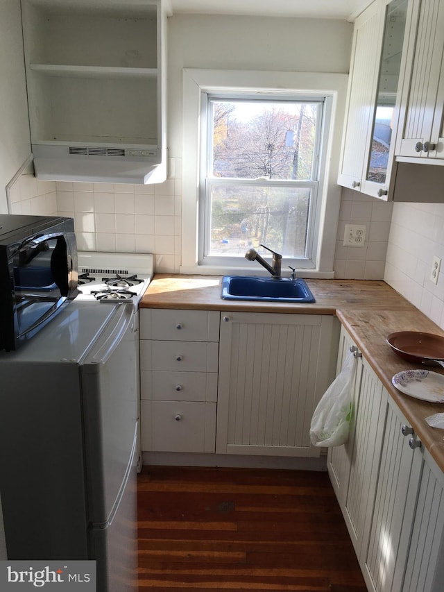 kitchen featuring white cabinets, backsplash, butcher block counters, and sink