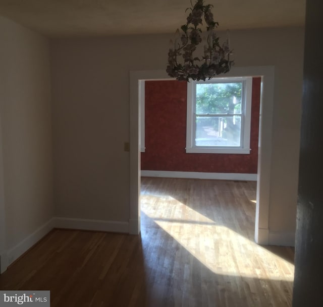 unfurnished dining area featuring wood-type flooring and a notable chandelier