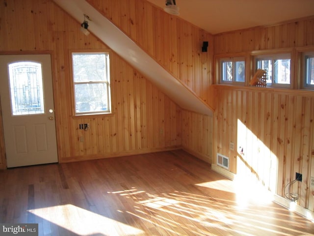 additional living space with wood-type flooring and wooden walls