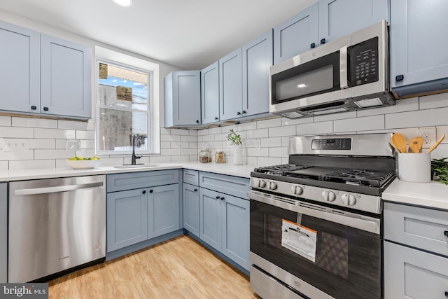 kitchen with sink, light hardwood / wood-style flooring, stainless steel appliances, and tasteful backsplash