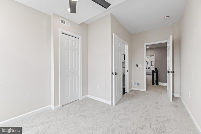 unfurnished bedroom with ceiling fan, light colored carpet, and a closet