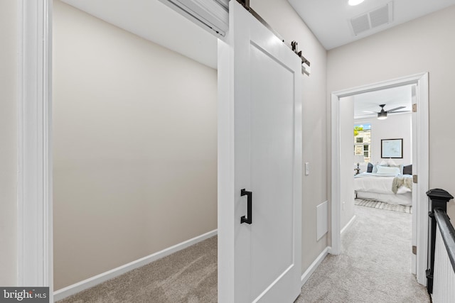 hallway with light carpet and a barn door