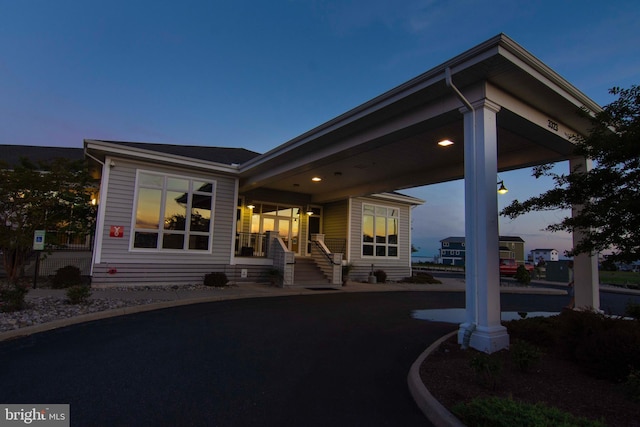 back house at dusk featuring covered porch