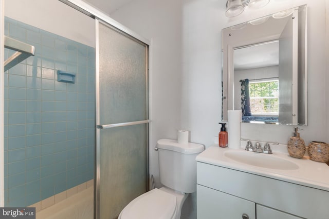 bathroom with a shower with shower door, vanity, and toilet