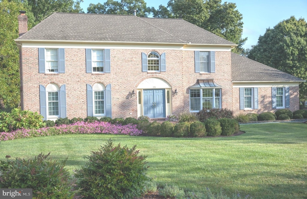 colonial house featuring a front lawn