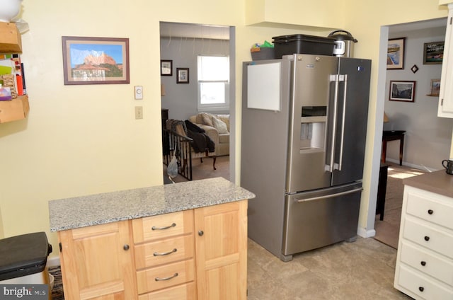 kitchen with light brown cabinetry, high end refrigerator, and light stone counters