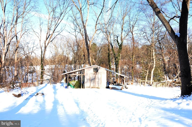 yard layered in snow featuring a shed