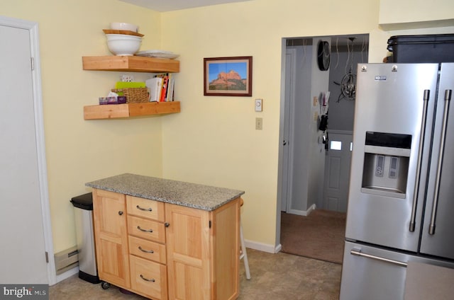 kitchen featuring light stone counters, light brown cabinetry, and stainless steel fridge