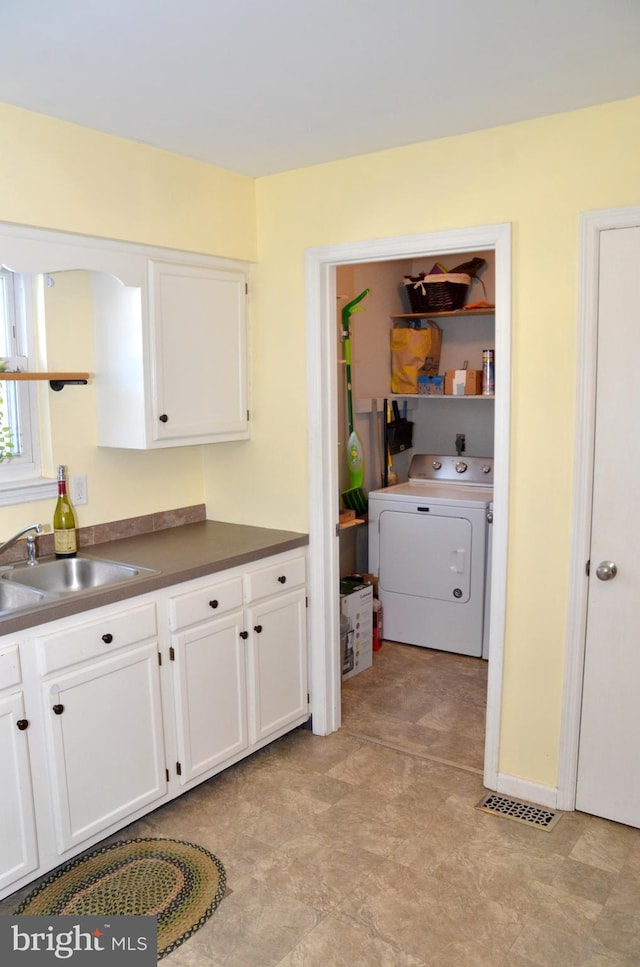 kitchen with white cabinets, washer / dryer, and sink