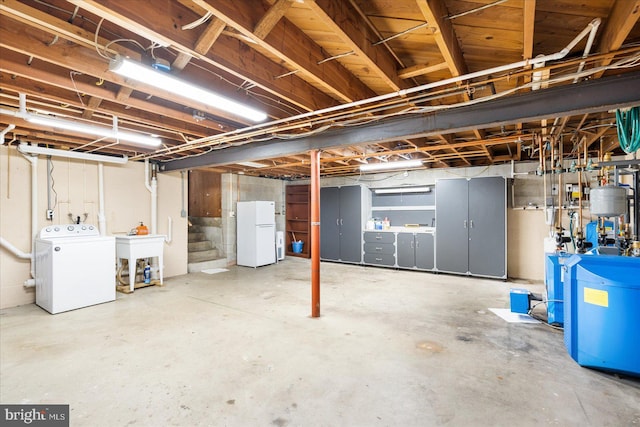 unfinished below grade area featuring stairs, separate washer and dryer, a sink, and freestanding refrigerator