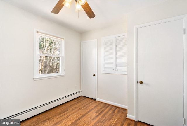 unfurnished bedroom with ceiling fan, baseboards, baseboard heating, and wood finished floors