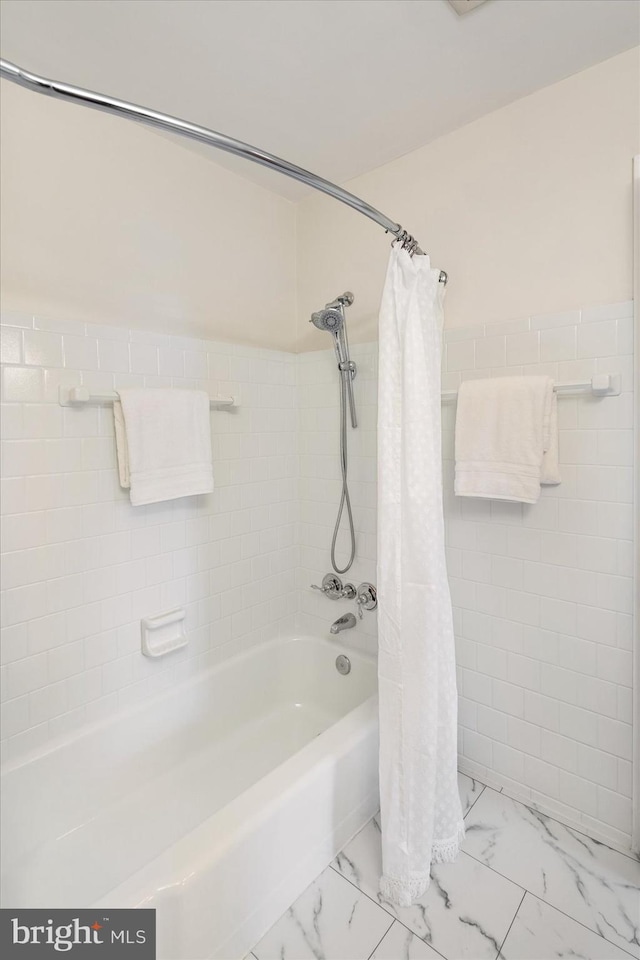 bathroom featuring marble finish floor, tile walls, and shower / tub combo with curtain