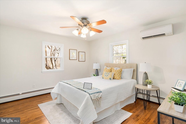 bedroom with an AC wall unit, ceiling fan, baseboard heating, and wood finished floors