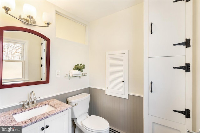 bathroom with a wainscoted wall, toilet, a baseboard heating unit, wood walls, and vanity