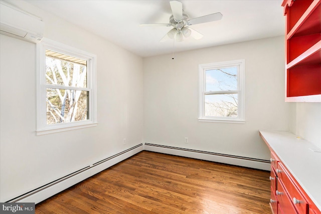 unfurnished room featuring an AC wall unit, a baseboard radiator, wood finished floors, and a ceiling fan