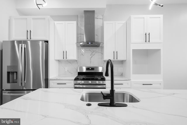 kitchen with white cabinetry, appliances with stainless steel finishes, backsplash, light stone countertops, and wall chimney range hood