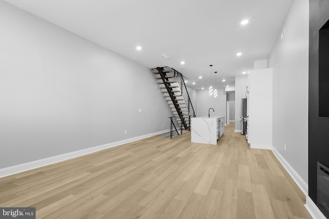 unfurnished living room featuring sink and light hardwood / wood-style floors