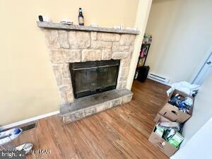 room details featuring a baseboard heating unit, a fireplace, and hardwood / wood-style flooring