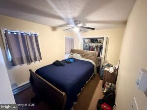 bedroom featuring ceiling fan, a closet, and baseboard heating