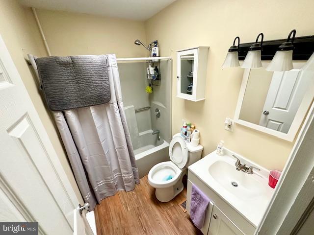 full bathroom with toilet, shower / bath combo, wood-type flooring, and vanity