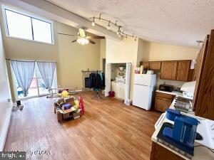 kitchen with a textured ceiling, white refrigerator, rail lighting, ceiling fan, and light hardwood / wood-style flooring