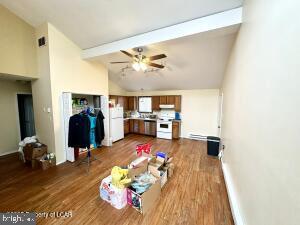 living room featuring ceiling fan, dark hardwood / wood-style flooring, and vaulted ceiling with beams