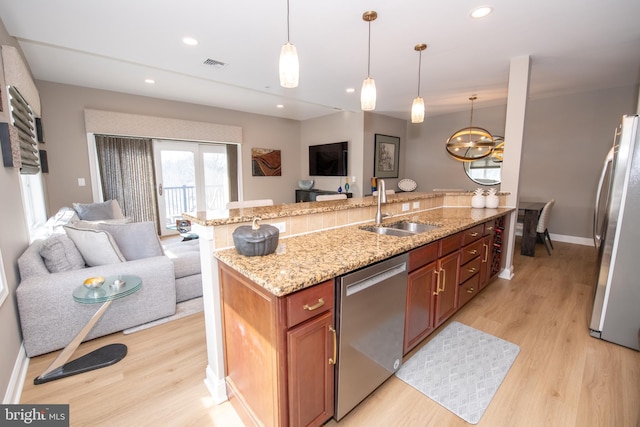 kitchen with sink, light hardwood / wood-style flooring, hanging light fixtures, stainless steel appliances, and light stone counters