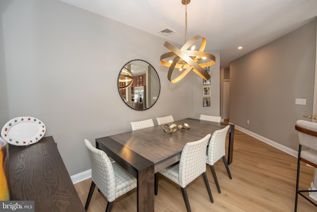 dining room with light hardwood / wood-style floors and a notable chandelier