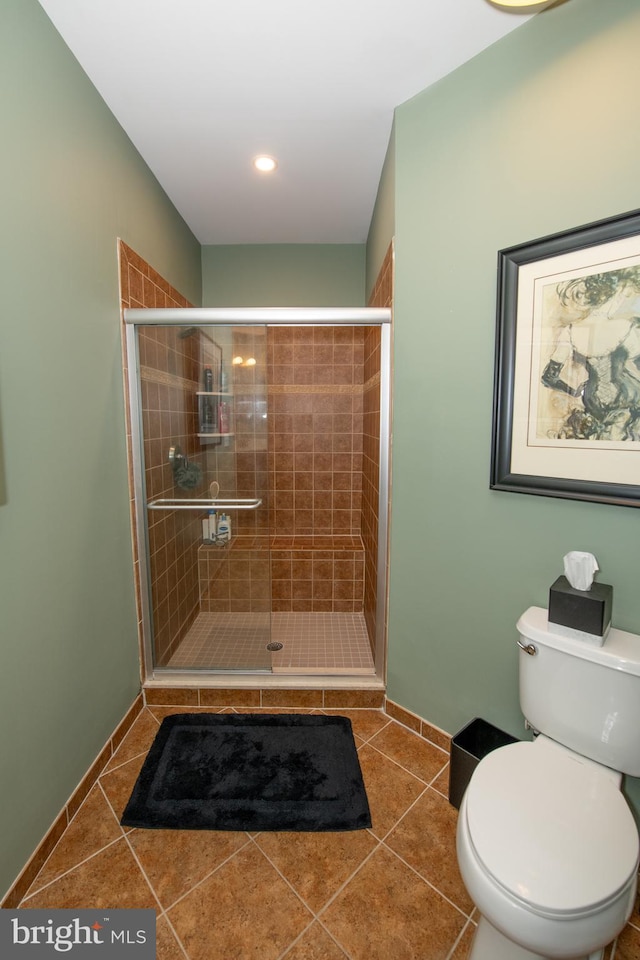 bathroom featuring a shower with shower door, tile patterned floors, and toilet