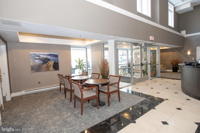 dining space featuring a baseboard radiator, french doors, and a high ceiling