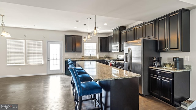 kitchen with decorative light fixtures, dark hardwood / wood-style floors, a center island, sink, and stainless steel appliances