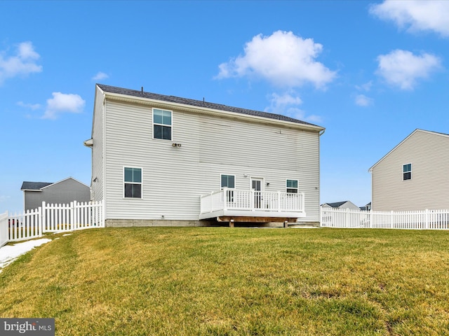 back of property with a deck and a yard