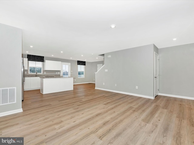 unfurnished living room with light hardwood / wood-style floors and sink