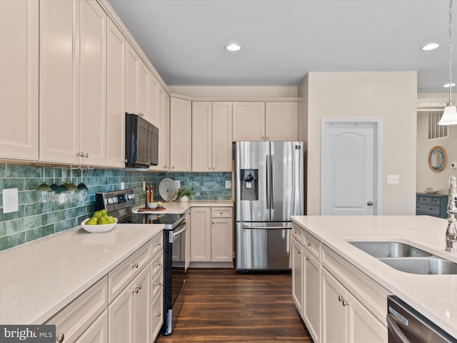 kitchen with dark wood-type flooring, sink, appliances with stainless steel finishes, pendant lighting, and light stone countertops