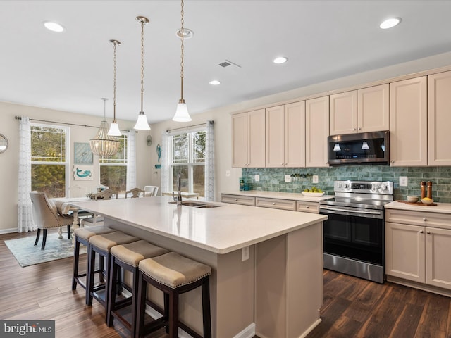 kitchen featuring sink, decorative light fixtures, a center island with sink, appliances with stainless steel finishes, and backsplash