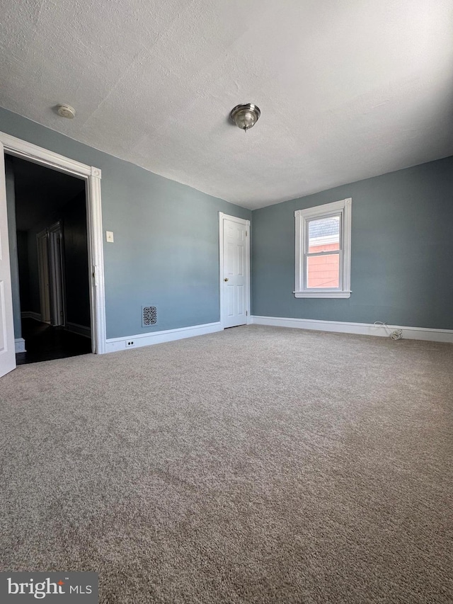 spare room with a textured ceiling and carpet floors