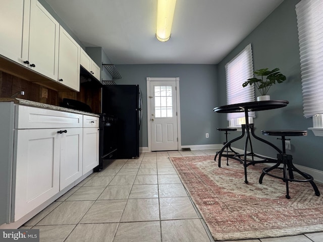 kitchen with white cabinetry and black fridge