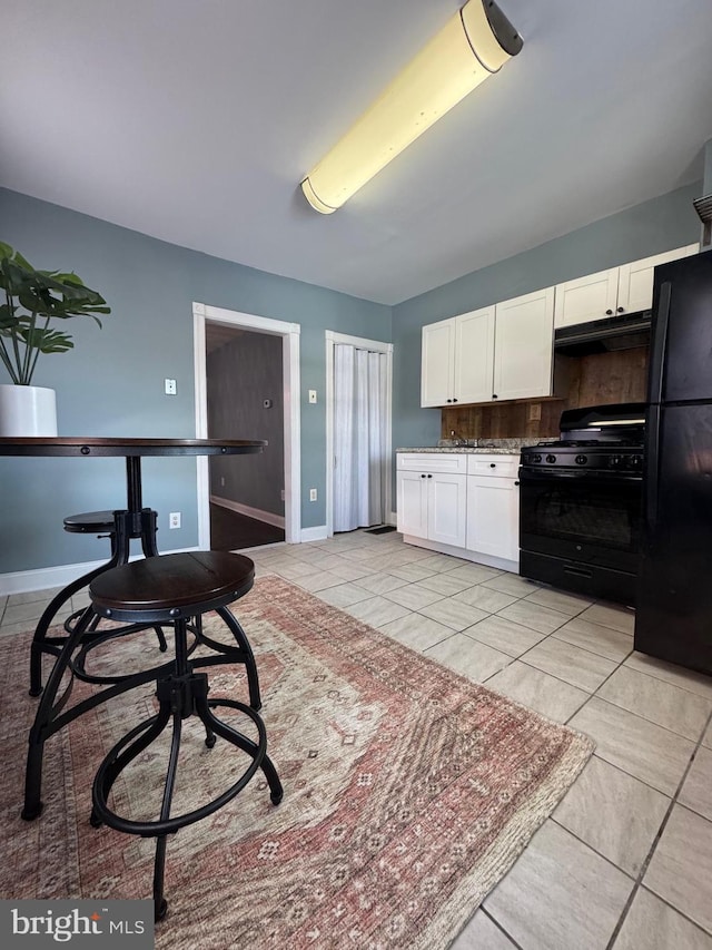 kitchen with black appliances, light tile patterned floors, and white cabinetry