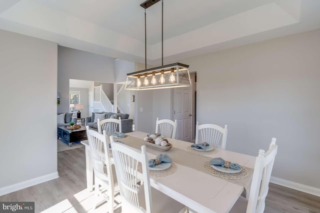 dining space featuring a tray ceiling and light hardwood / wood-style flooring