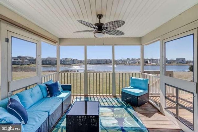 sunroom with ceiling fan and a water view