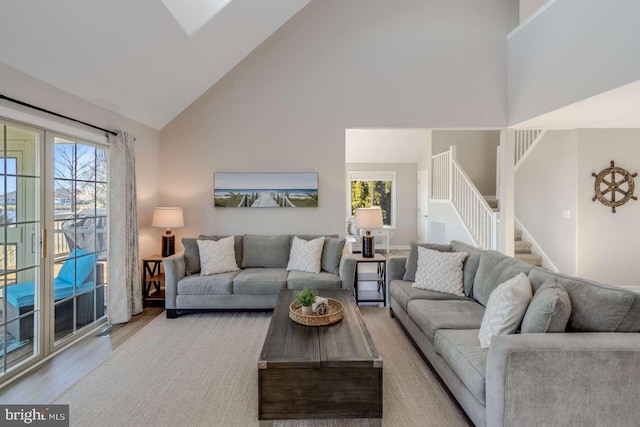 living room with high vaulted ceiling, a wealth of natural light, and light hardwood / wood-style floors