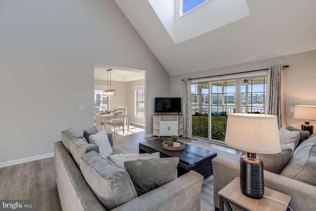 living room with light wood-type flooring, a healthy amount of sunlight, and high vaulted ceiling