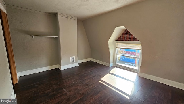 empty room with dark wood-type flooring and a textured ceiling