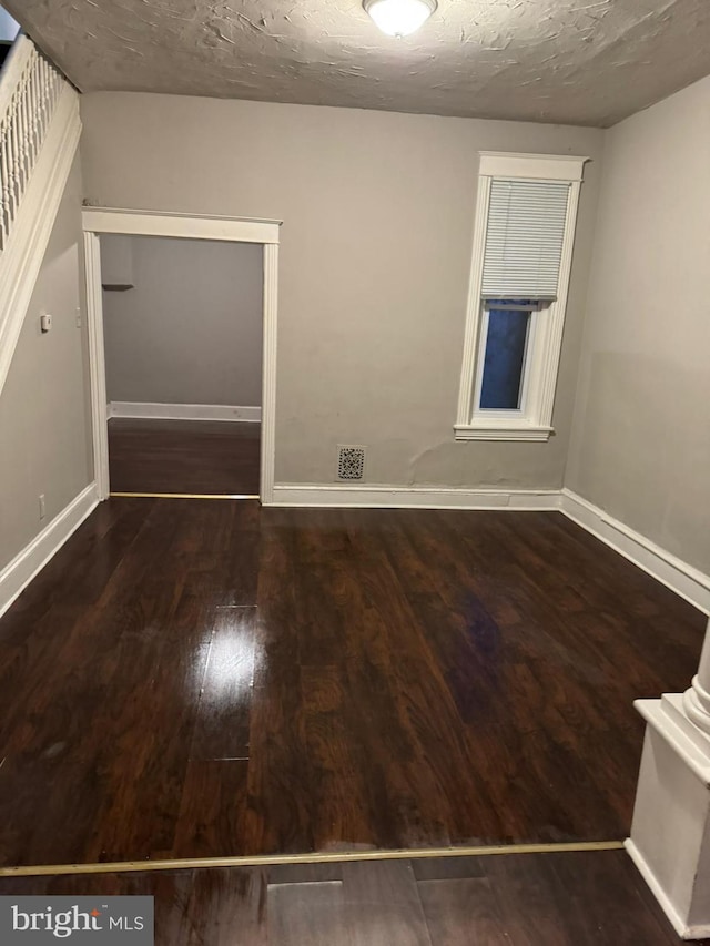 unfurnished room featuring a textured ceiling and dark hardwood / wood-style floors